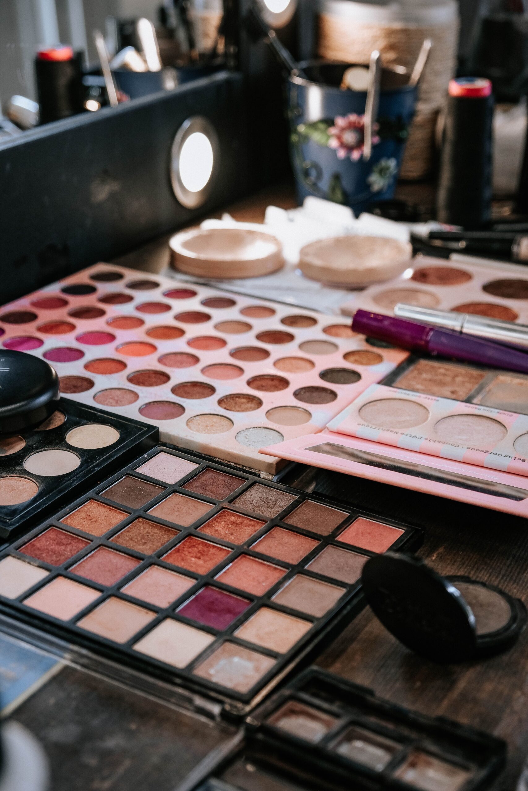 Colorful eyeshadow palettes and face makeup products displayed on a makeup artist's workstation